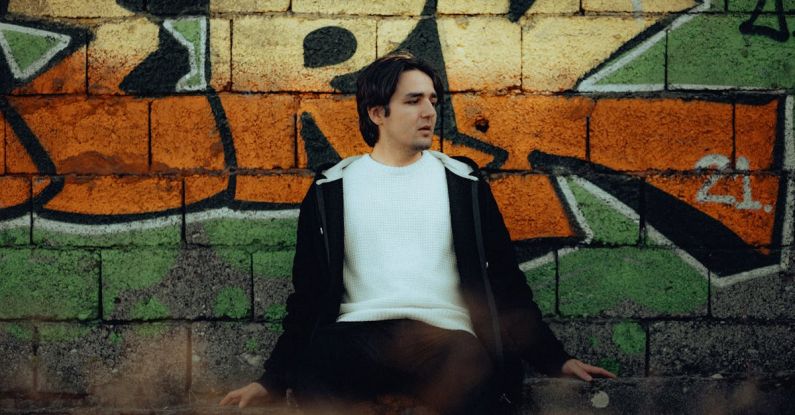 Backsplash Colors - A man sitting on a bench in front of a graffiti wall