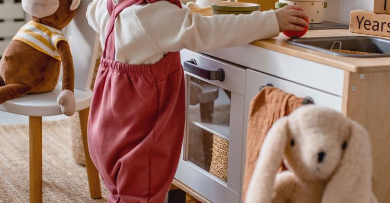 Small Kitchens - Baby in a Chef Hat Playing with a Toy Kitchen in a Chef Hat