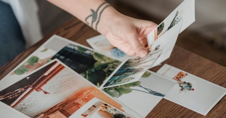 High-End Look - High angle anonymous female looking through printed pictures scattered on table in light room