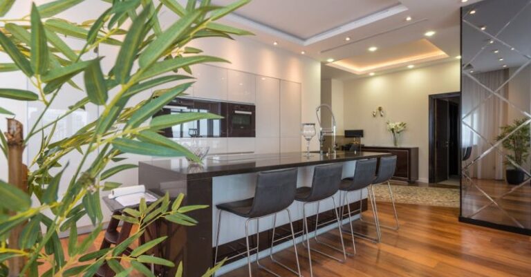 Kitchen Islands - Kitchen island with black leather chairs in spacious modern apartment with white minimalist furniture and built in appliances